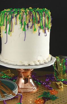 a white cake with green, yellow and purple icing sitting on top of a table