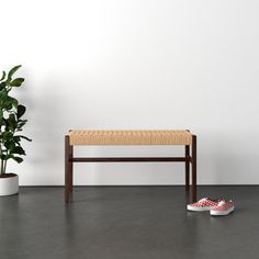 a wooden bench sitting next to a potted plant on top of a hard wood floor