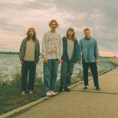 four young men standing next to each other near the water