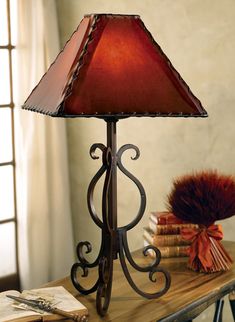 a red lamp sitting on top of a wooden table next to a stack of books