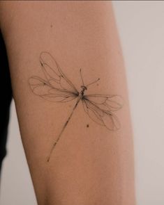 a dragonfly tattoo on the back of a woman's arm