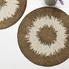 two brown and white woven placemats next to a vase with flowers in it