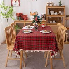 a dining room table set for two with place settings and christmas decorations on the wall