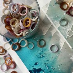 there are many rings in the bowl on the table next to some other items that have been made from them