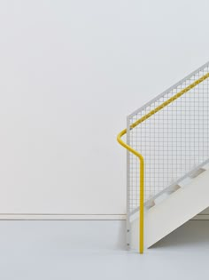 a yellow hand rail next to a white stair case