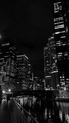 a black and white photo of the city at night with lights reflecting in the water