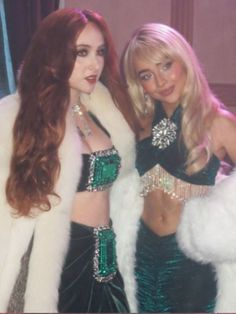 two beautiful women dressed in costumes posing for a photo with one woman wearing a fur coat