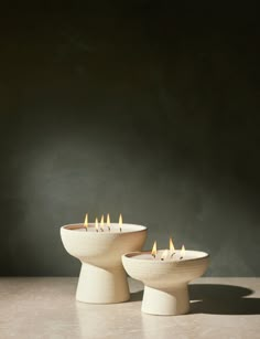 two white candles sitting on top of a table