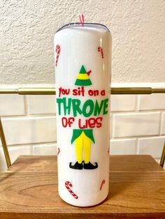 a white can sitting on top of a wooden table next to a red and green christmas decoration