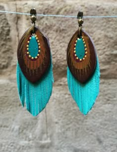 two brown and turquoise earrings hanging from a clothes line