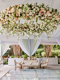 an elegant wedding setup with white and pink flowers hanging from the ceiling, along with draping