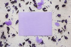 purple paper surrounded by leaves and petals on a wooden surface with space for text or image