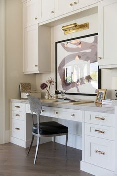 a desk with a chair and pictures on the wall above it in a home office