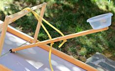 a wooden frame with a plastic container on top and some yellow cords attached to it