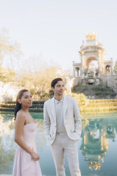 a man and woman standing next to each other in front of a body of water