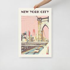 a person holding up a new york city poster in front of a white wall with the brooklyn bridge on it