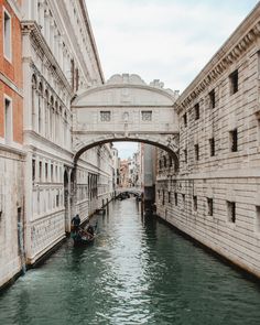 two gondolas are in the water under an arched bridge over a narrow canal