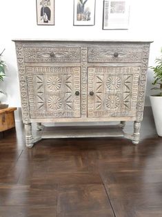 an old dresser is painted white and decorated with pictures on the wall, along with potted plants