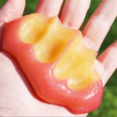 a close up of a person's hand holding an orange and yellow piece of food