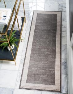 an area rug on the floor next to a table with a potted plant in it