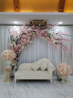 a white couch sitting under a pink flower covered arch