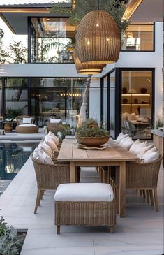 an outdoor dining area with wicker furniture and large glass doors leading to the pool