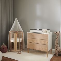 a baby's room with a crib, dresser and stuffed giraffe