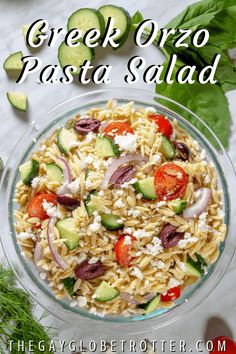 greek orzo pasta salad in a glass bowl with cucumbers and tomatoes on the side