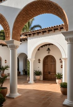 an outdoor courtyard with arches and potted plants