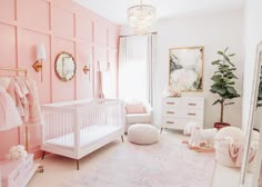 a baby's room with pink walls and white crib in the corner, large mirror on the wall