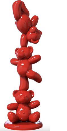 a red teddy bear sculpture sitting on top of a pile of other bears in front of a white background