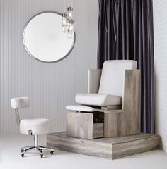 a white chair sitting on top of a wooden platform in front of a round mirror