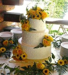 a wedding cake with sunflowers and greenery