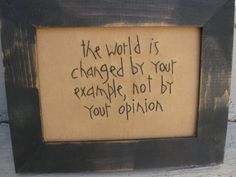 a wooden frame with writing on it that says the world is changed by your example, not by your opinion