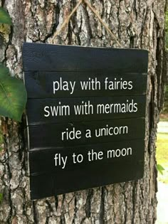 a sign on a tree that says play with fairiess swim with mermaids ride a unicorn fly to the moon