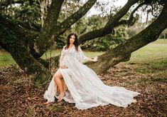 a woman in a white dress sitting on a tree