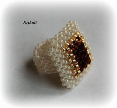 a close up of a beaded ring on a white surface with the words sekui written below it