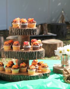 cupcakes are stacked on top of each other with flowers in vases next to them