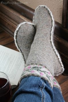 someone is reading a book with their feet propped up next to a glass of wine