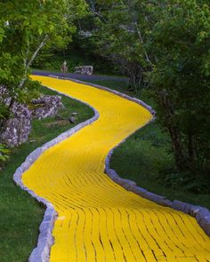 a yellow walkway is painted in the shape of a brick road with trees around it