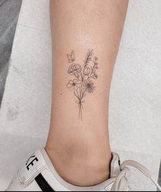 a woman's foot with a small flower tattoo on the left side of her leg