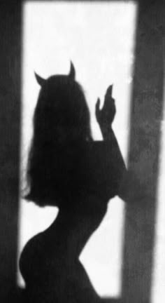 the silhouette of a woman with horns on her head is shown in black and white