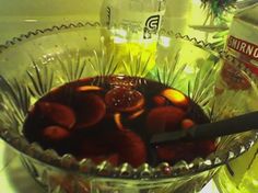 a glass bowl filled with fruit next to bottles