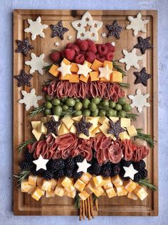 a christmas tree made out of fruits and cheeses on a cutting board with stars