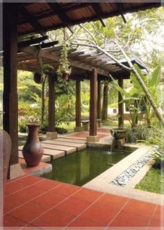 an outdoor patio with a pond and seating area in the middle, surrounded by greenery