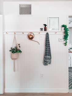 a white wall with some plants and towels hanging from it's hooks on the wall