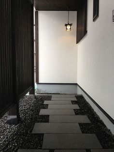 an empty hallway with black and white tiles on the floor next to a light fixture