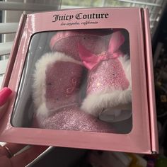 a pink box that has some baby shoes inside of it with glitter on the bottom