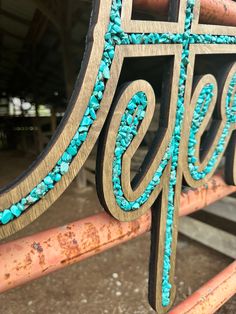 an ornate wooden sign with turquoise beads on it