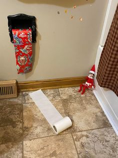 a roll of toilet paper sitting on the floor next to a elf's hat